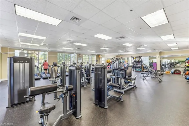 The fitness center features a variety of exercise equipment, including treadmills and weight machines, with large windows providing natural light