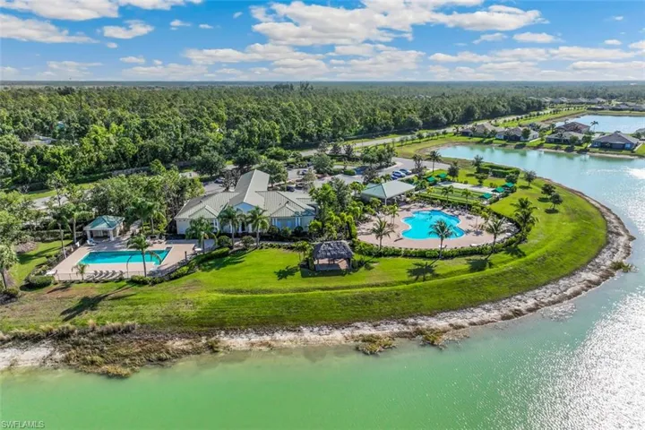 The property features a clubhouse with a large swimming pool, surrounded by paved lounging areas and palm trees