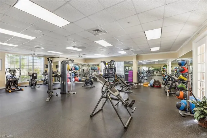 The property features an extensive fitness center with a variety of exercise equipment, large windows, and mirrored walls