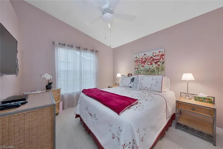 Bedroom with ceiling fan, light carpet, and vaulted ceiling