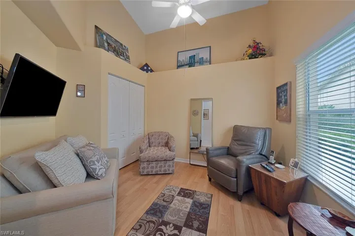 Living room featuring light hardwood / wood-style flooring, ceiling fan, and high vaulted ceiling