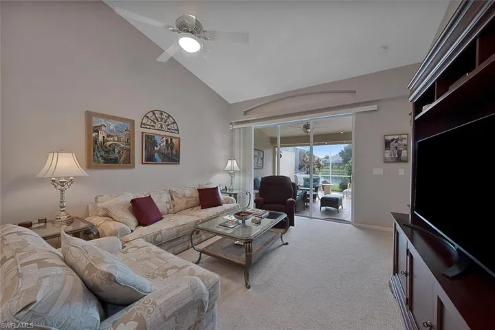 Carpeted living room featuring high vaulted ceiling and ceiling fan