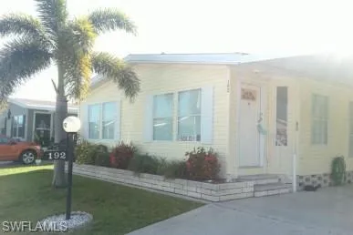 View of front of property with entry steps, a front lawn, and a carport
