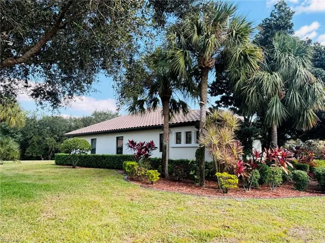 View of side of property with a lawn, stucco siding, and a tiled roof