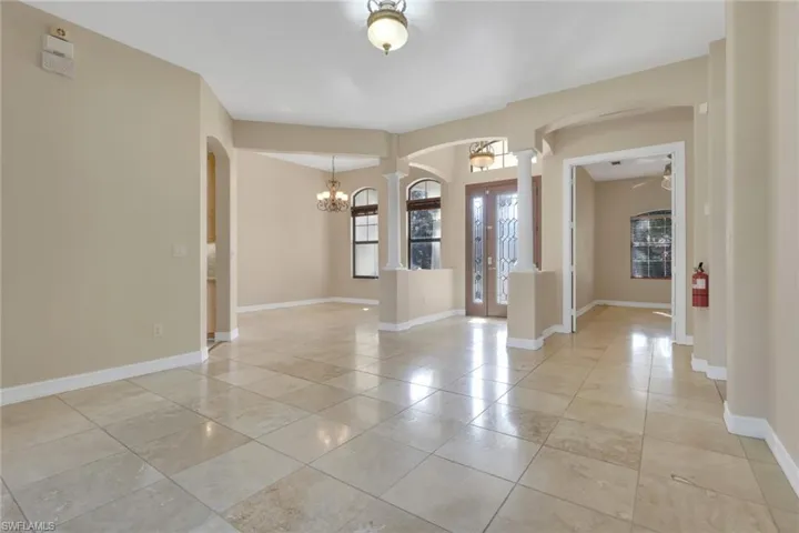 Entrance foyer featuring arched walkways, a ceiling fan, a chandelier, and light tile patterned flooring