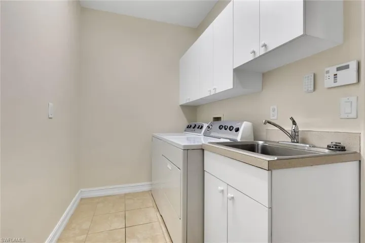Laundry room with light tile patterned floors, cabinet space, and washing machine and dryer