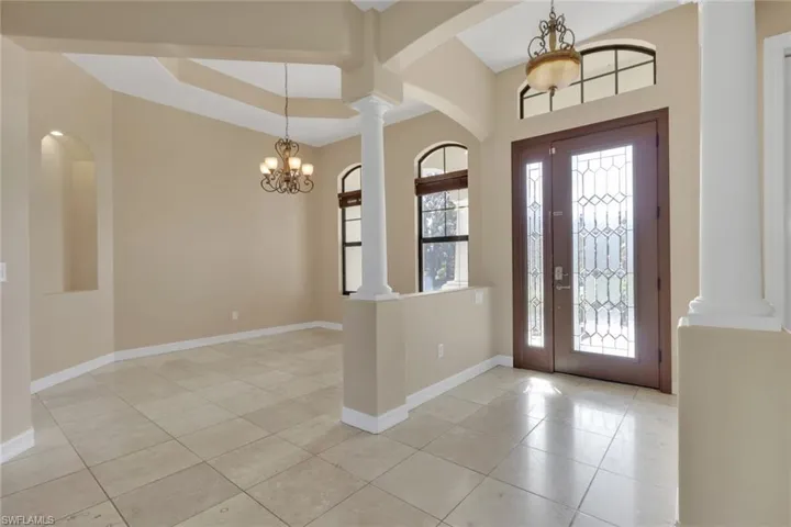 Foyer with a chandelier, light tile patterned floors, and ornate columns