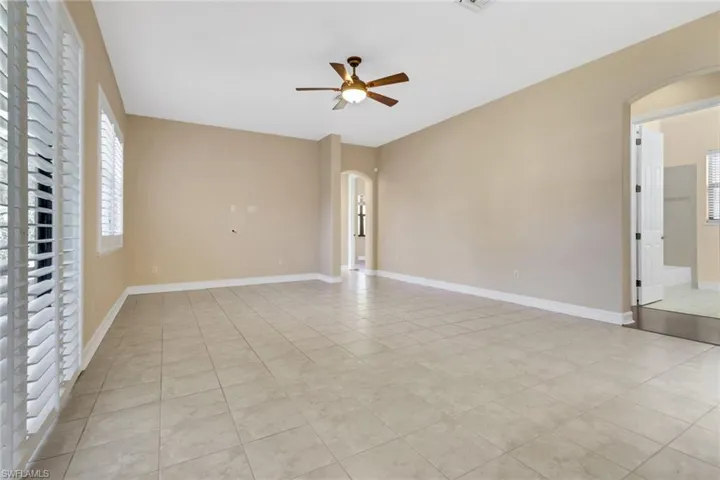 Empty room with arched walkways, ceiling fan, and light tile patterned floors