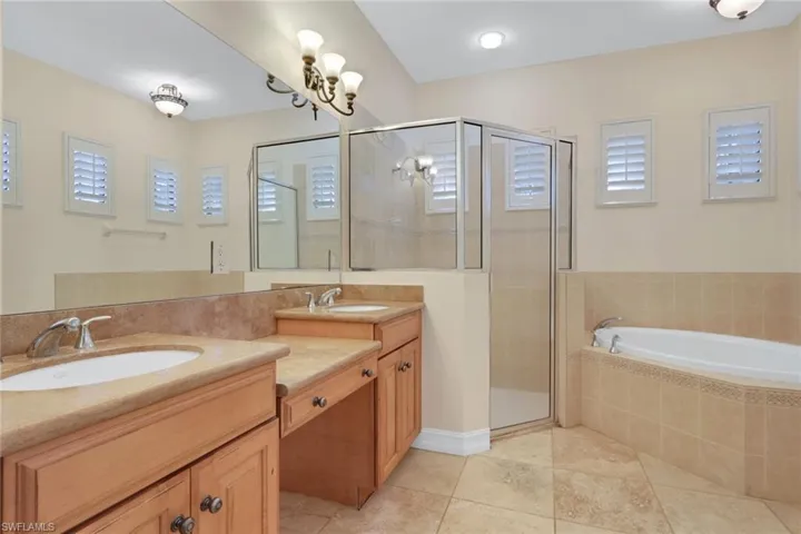 Bathroom featuring double vanity, a bath, a shower stall, and light tile patterned floors