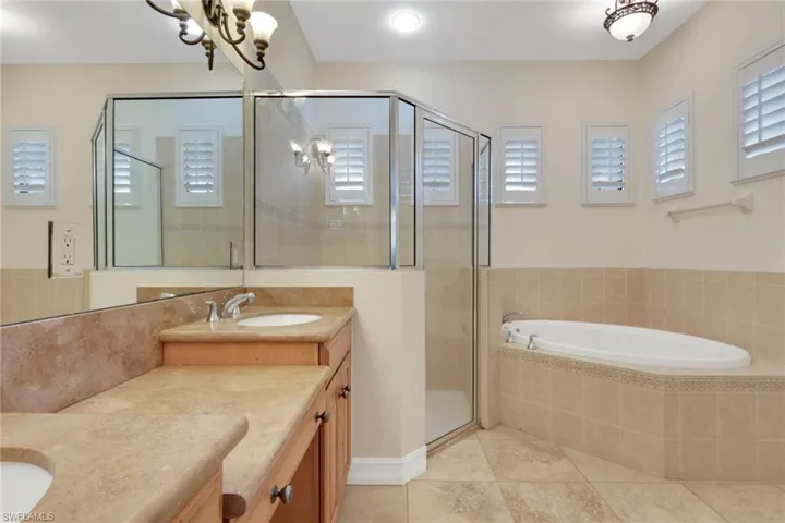 Full bath featuring double vanity, a bath, a shower stall, and light tile patterned flooring