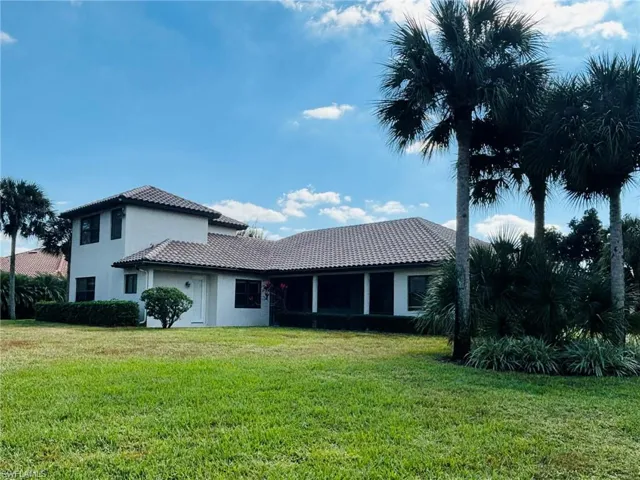 Rear view of house featuring a lawn, a tiled roof, and stucco siding