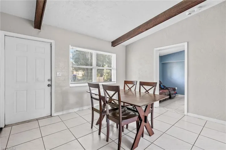 Tiled dining space featuring vaulted ceiling with beams