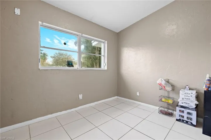 Empty room with light tile patterned floors and lofted ceiling