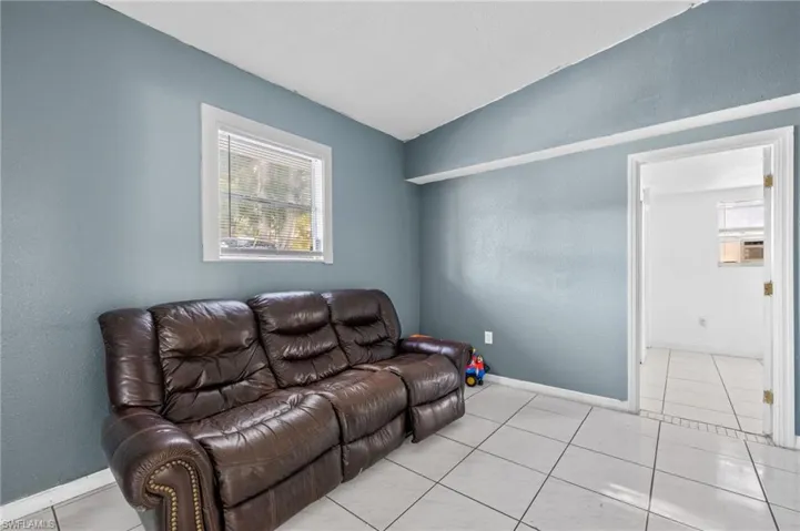 Living room with cooling unit, light tile patterned floors, and lofted ceiling