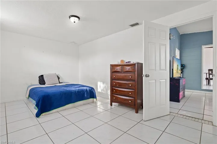 Bedroom featuring lofted ceiling, light tile patterned floors, and a textured ceiling