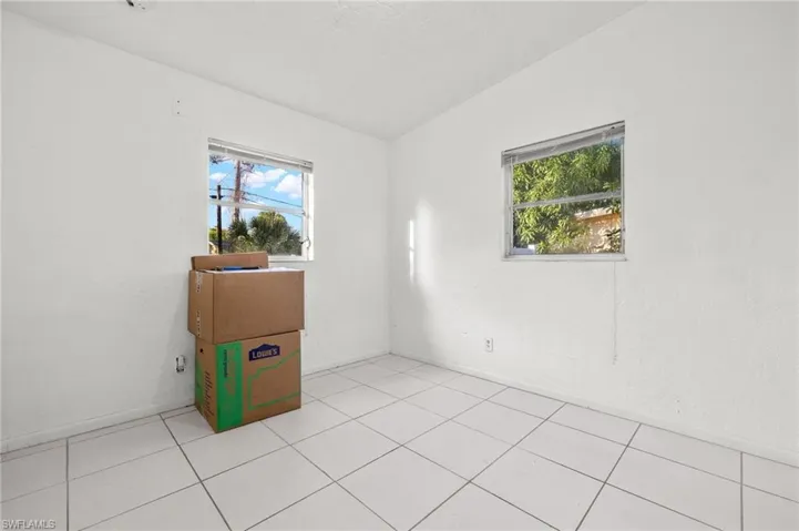 Tiled empty room featuring vaulted ceiling and a wealth of natural light