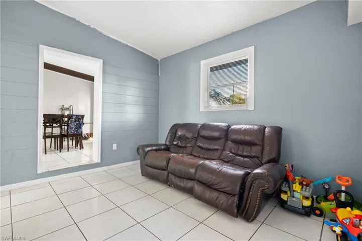 Tiled living room featuring vaulted ceiling