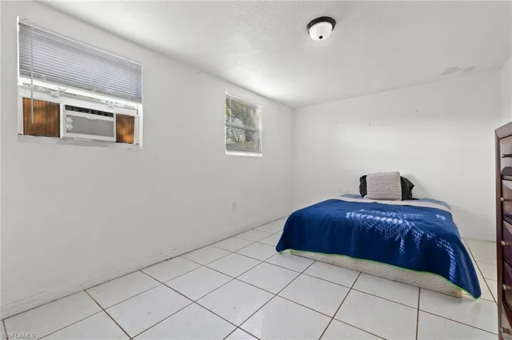 Bedroom with light tile patterned floors, a textured ceiling, and cooling unit