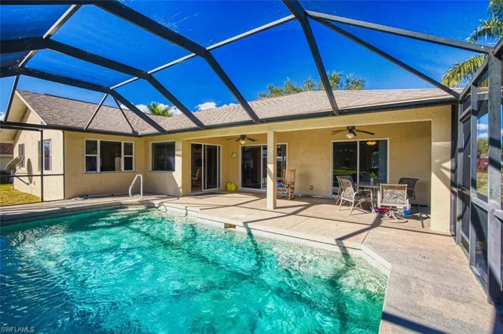 Back of property featuring stucco siding, a sunroom, a lanai, a patio, and an outdoor pool