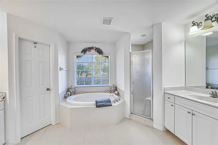 Bathroom with vanity, a stall shower, a bath, and light tile patterned flooring