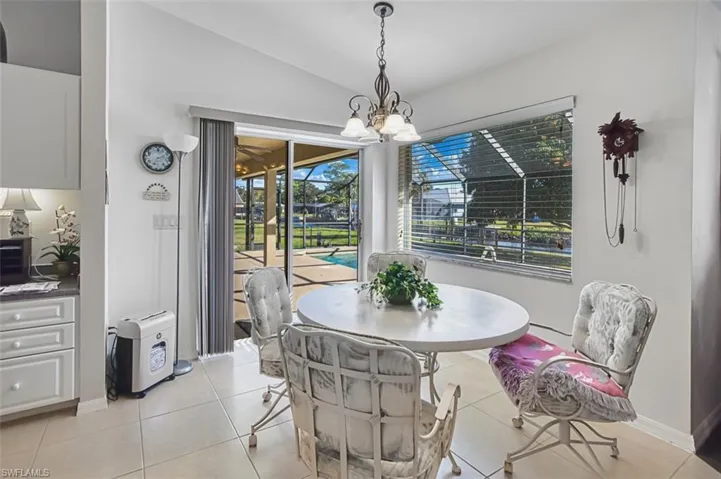 Dining area featuring lofted ceiling, light tile patterned floors, a chandelier, and a sunroom