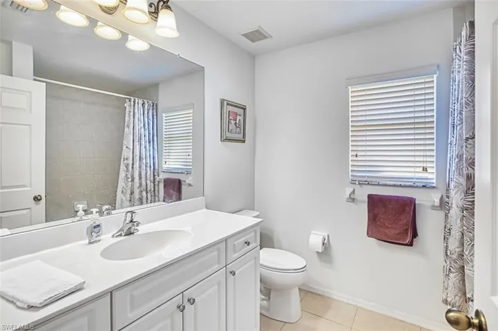 Bathroom featuring vanity, light tile patterned floors, and curtained shower