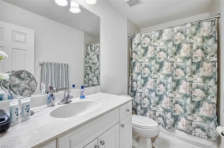 Bathroom featuring vanity and shower / bathtub combination with curtain