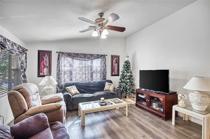 Living area with vaulted ceiling, wood finished floors, and ceiling fan