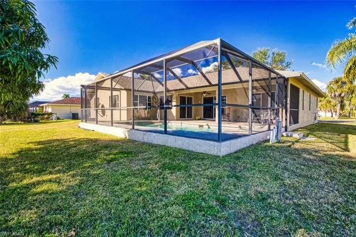 Back of house with a sunroom, a lanai, an outdoor pool, ceiling fan, and a yard