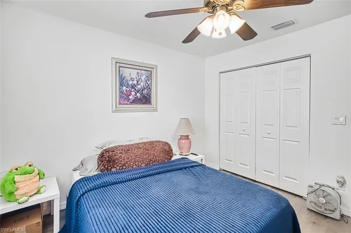 Bedroom with wood finished floors, ceiling fan, and a closet