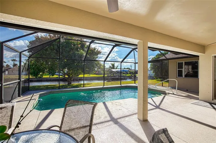 Swimming pool featuring a sunroom, a patio area, a water view, and a lanai