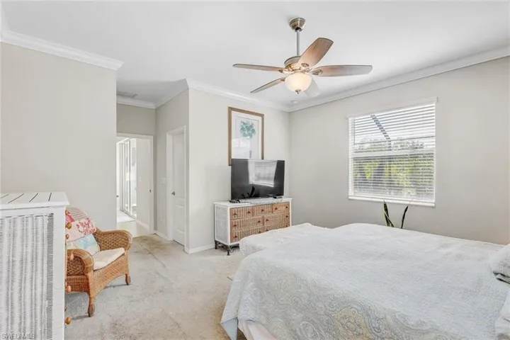 Carpeted bedroom with crown molding and ceiling fan