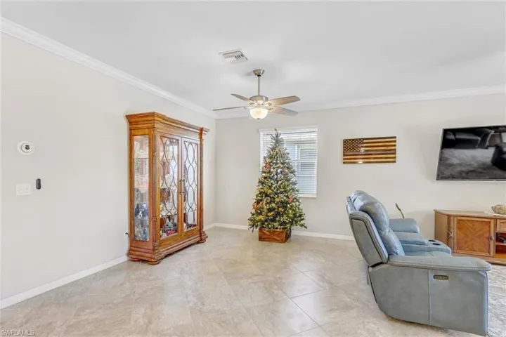 Living area featuring ornamental molding, a ceiling fan, and tile patterned floors