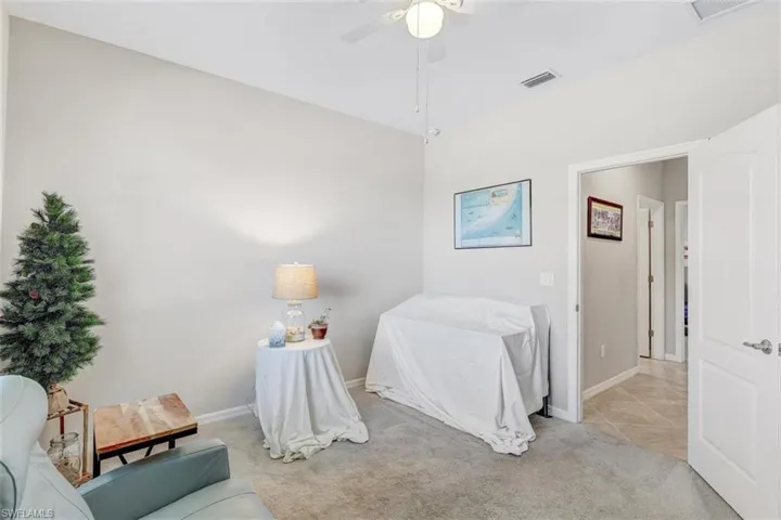 Carpeted bedroom featuring a ceiling fan and tile patterned floors