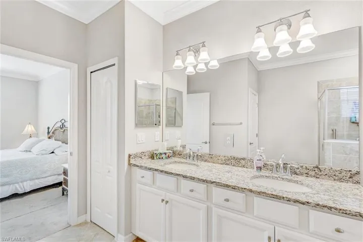 Ensuite bathroom with a closet, ornamental molding, double vanity, a stall shower, and light tile patterned floors