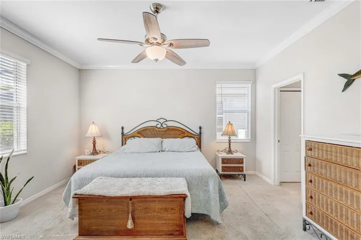 Bedroom with crown molding, light carpet, and a ceiling fan