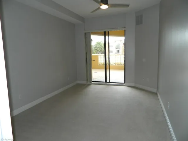 Carpeted living area featuring a ceiling fan and baseboards