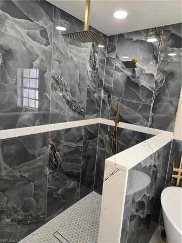 Master bathroom Full bath featuring tile walls, a marble finish shower, and a soaking tub