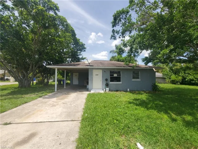 View of front of home with a carport and a front lawn