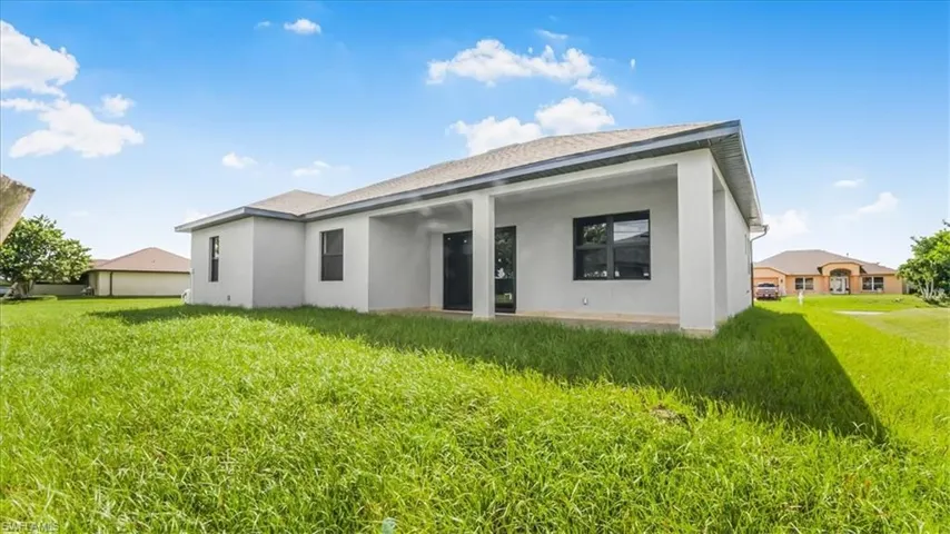 Back of house with a lawn, stucco siding, and a patio