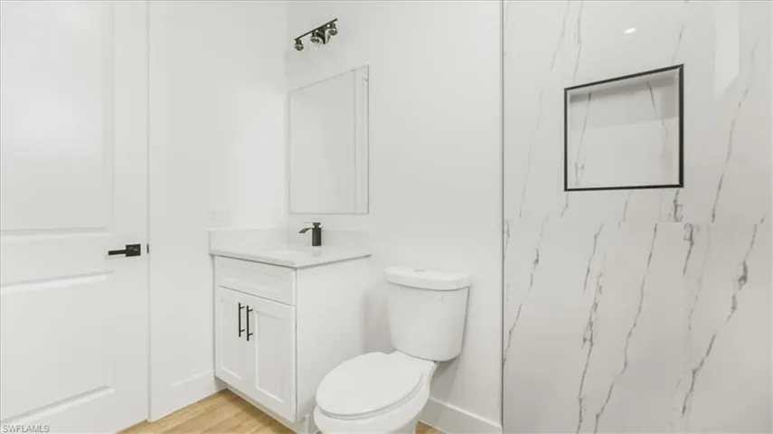 Full bathroom featuring vanity, light wood-style flooring, and a marble finish shower