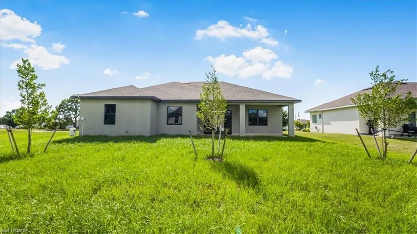 Rear view of property featuring a patio, stucco siding, a yard, and roof with shingles