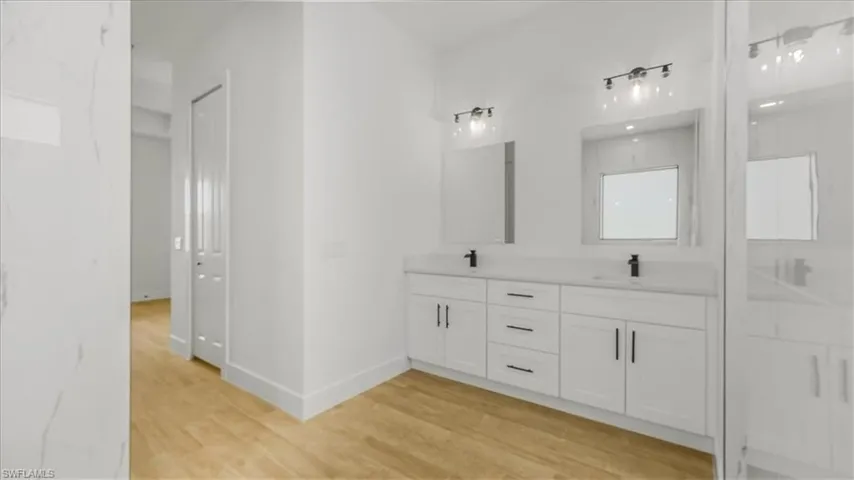 Full bath featuring double vanity and light wood-style floors