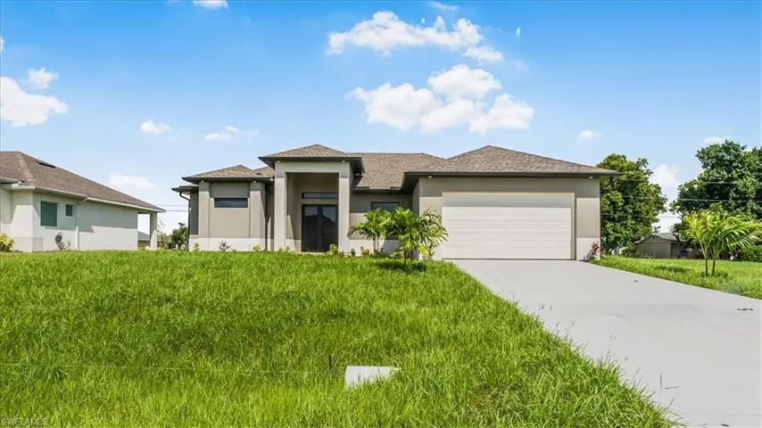 Prairie-style house with stucco siding, concrete driveway, a garage, roof with shingles, and a front yard