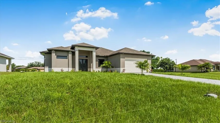 Prairie-style home with stucco siding, concrete driveway, a garage, and a front yard