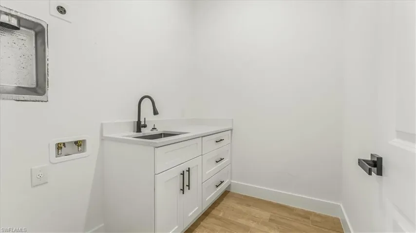 Washroom featuring cabinet space, hookup for a washing machine, and light wood-type flooring