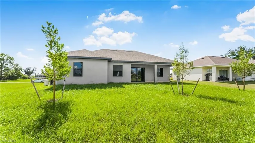 Back of house with a patio area, stucco siding, a yard, and a shingled roof