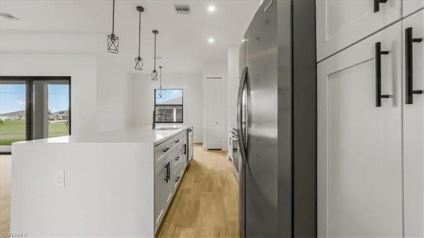 Kitchen featuring pendant lighting, stainless steel appliances, recessed lighting, light wood-type flooring, and an island with sink