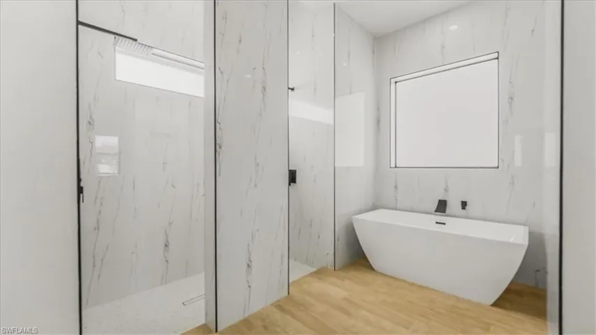 Full bath with a marble finish shower, a freestanding bath, and stone wall