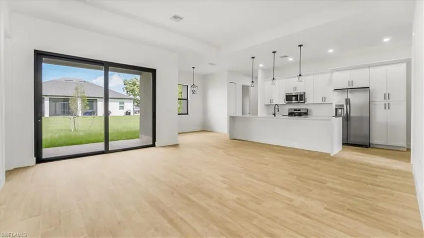 Unfurnished living room with recessed lighting, light wood-type flooring, and a tray ceiling